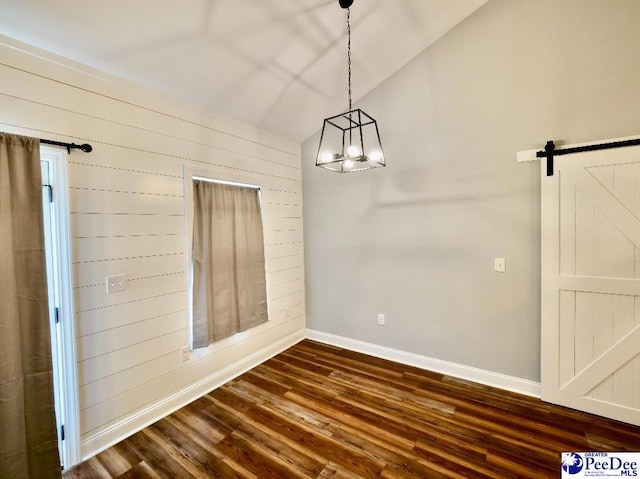 unfurnished dining area featuring wooden walls, baseboards, dark wood finished floors, a barn door, and vaulted ceiling