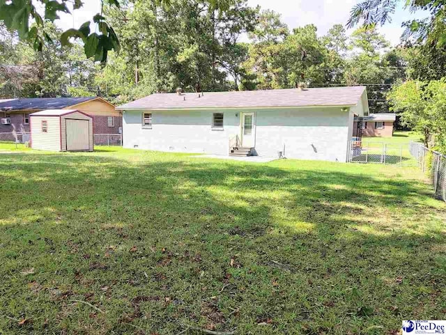 rear view of house with a storage unit and a lawn