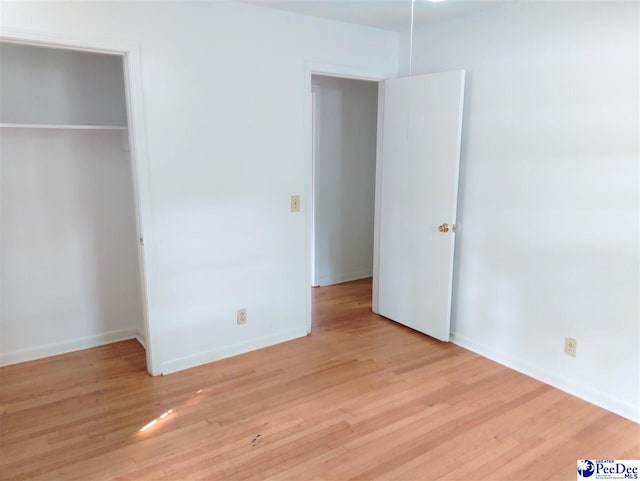 unfurnished bedroom featuring light hardwood / wood-style flooring and a closet