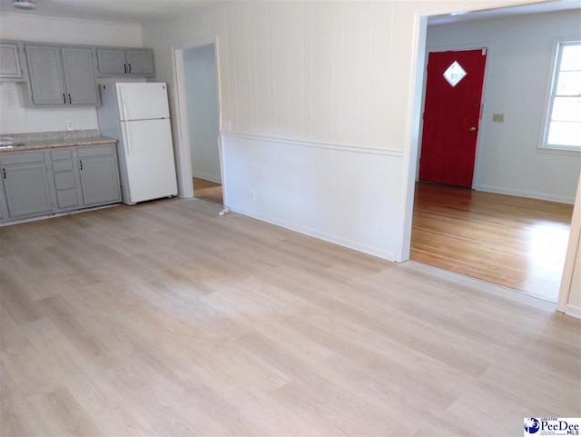 kitchen with gray cabinets, light hardwood / wood-style floors, and white refrigerator