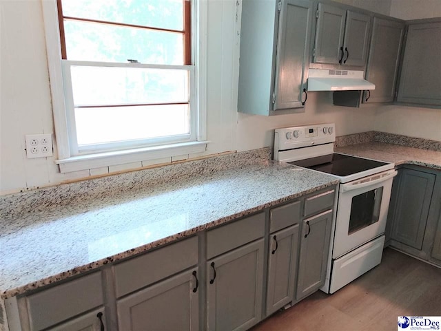 kitchen featuring gray cabinetry, white electric range, light stone countertops, and light wood-type flooring