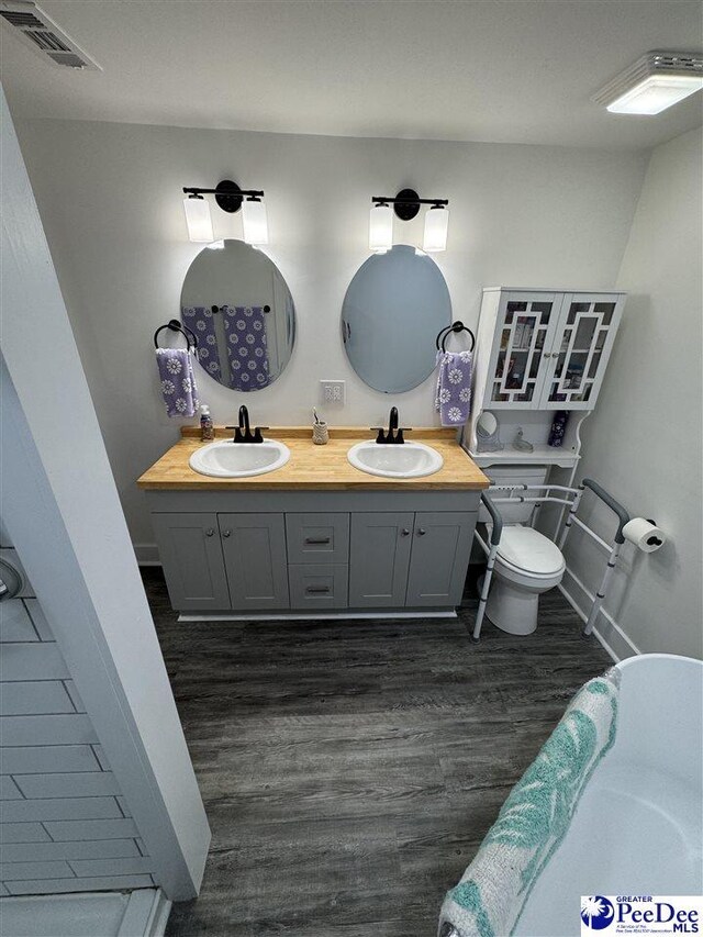 1770 Woods Dr, Florence, SC 29505 - full bathroom featuring toilet, visible vents, a sink, and wood finished floors