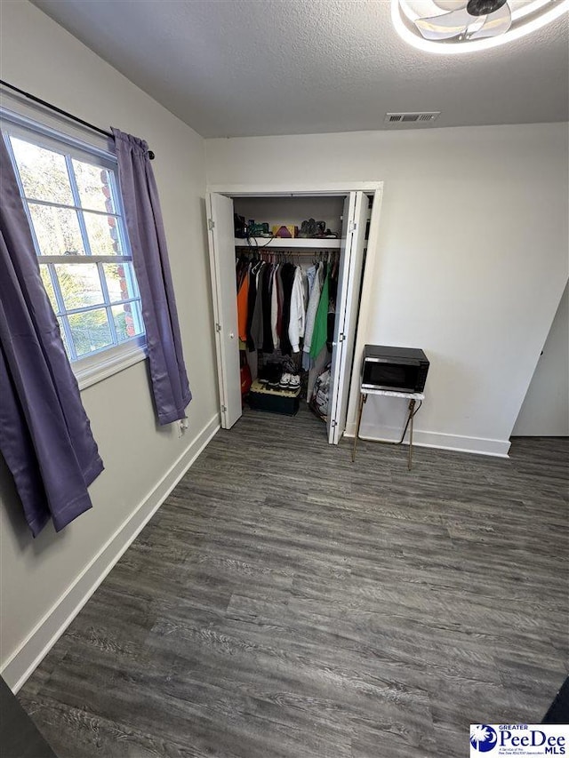 1770 Woods Dr, Florence, SC 29505 - unfurnished bedroom with a textured ceiling, visible vents, baseboards, a closet, and dark wood-style floors