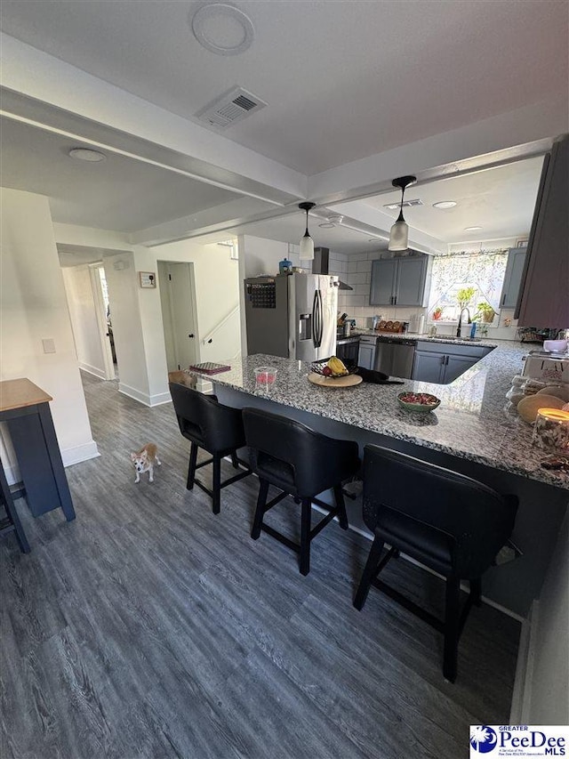 kitchen with gray cabinetry, visible vents, stainless steel refrigerator with ice dispenser, decorative backsplash, and dark wood finished floors