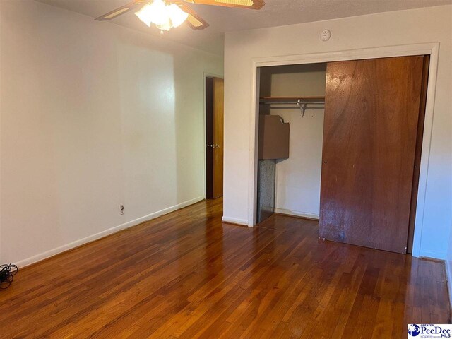 unfurnished bedroom featuring dark wood-type flooring, ceiling fan, and a closet