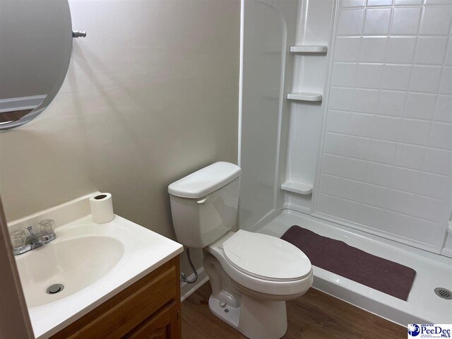 bathroom featuring walk in shower, vanity, toilet, and hardwood / wood-style floors