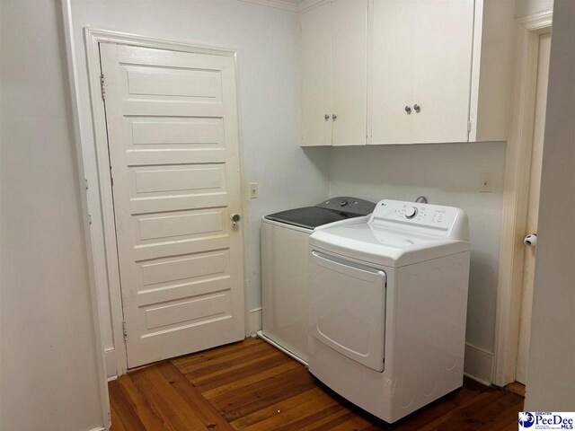 clothes washing area with cabinets, dark wood-type flooring, and washing machine and clothes dryer