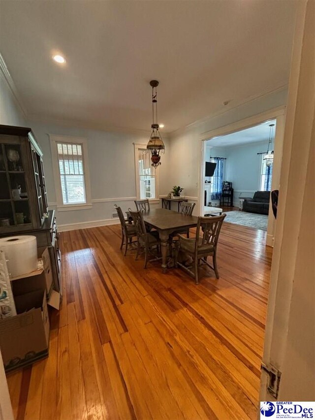 dining space with crown molding, an inviting chandelier, and light hardwood / wood-style floors