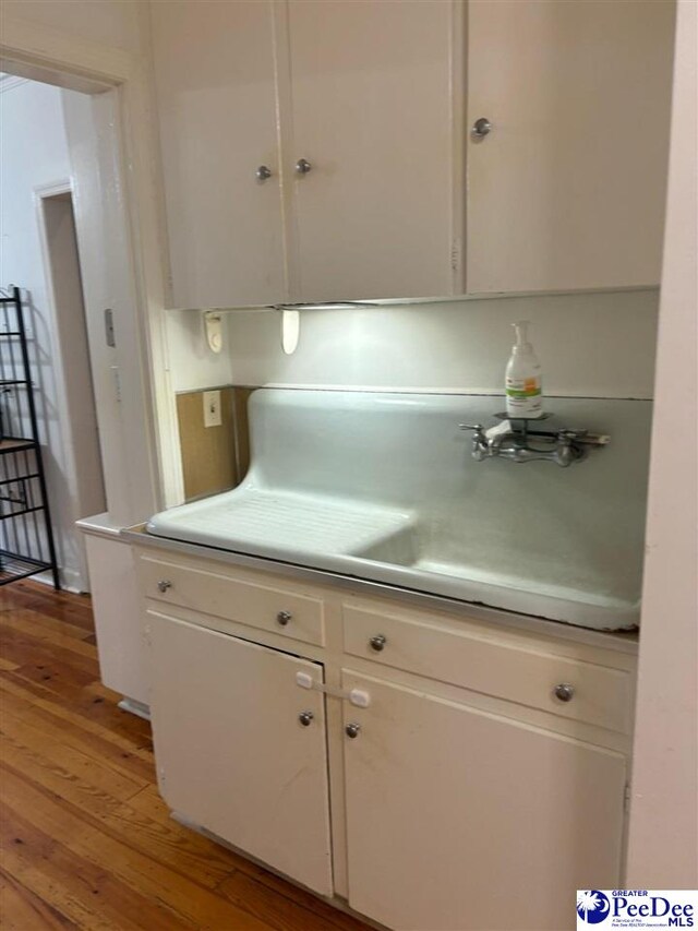 kitchen featuring sink, hardwood / wood-style floors, and white cabinets