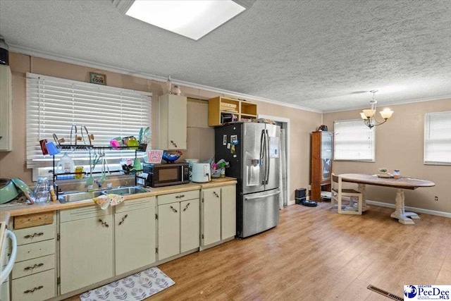 kitchen featuring stainless steel fridge with ice dispenser, crown molding, light countertops, light wood-type flooring, and a textured ceiling
