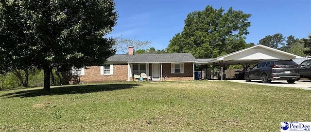 ranch-style home featuring a front lawn, brick siding, a carport, a chimney, and driveway