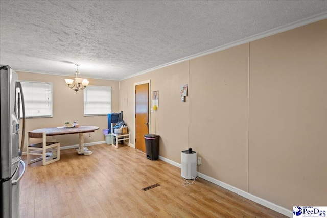 dining space with crown molding, a chandelier, light wood-style floors, a textured ceiling, and baseboards