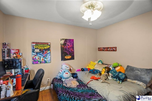 bedroom featuring wood finished floors, an office area, baseboards, and a ceiling fan