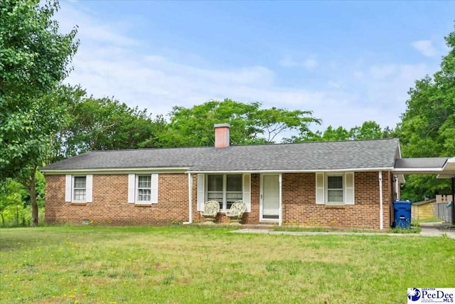 ranch-style home featuring a front yard, a chimney, brick siding, and a carport