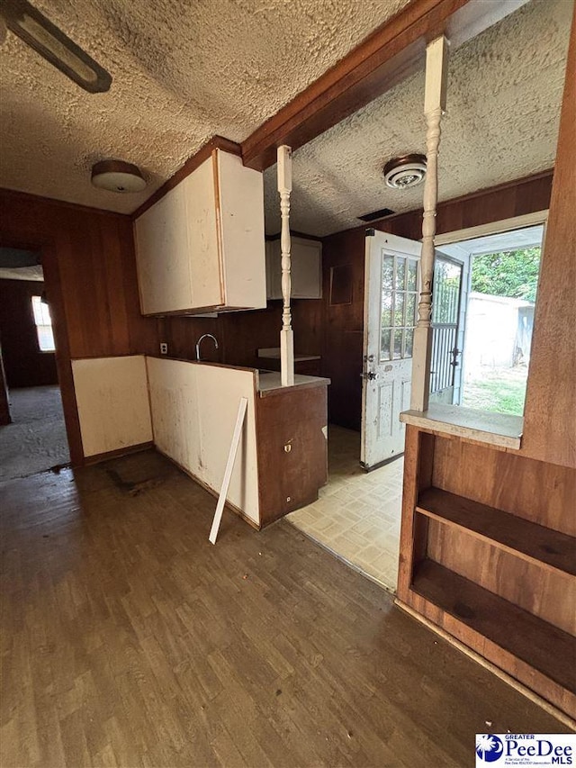 207 W Smith Ave, Darlington, SC 29532 - kitchen with wood finished floors, wooden walls, white cabinets, and a textured ceiling