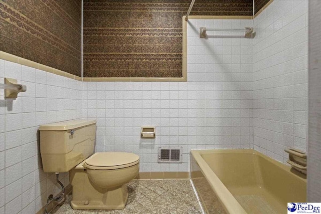 bathroom with tile walls, a bath, tile patterned flooring, and toilet