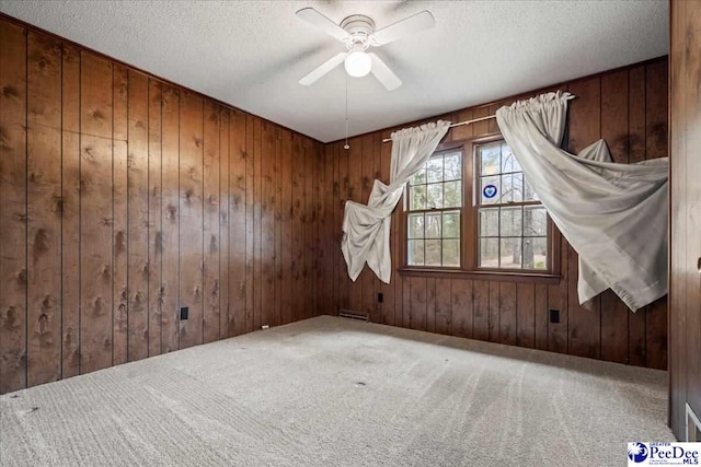 bonus room with ceiling fan, wooden walls, carpet floors, and a textured ceiling