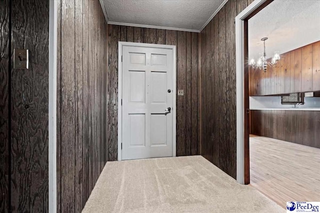 entryway with wood-type flooring, wooden walls, a notable chandelier, and a textured ceiling