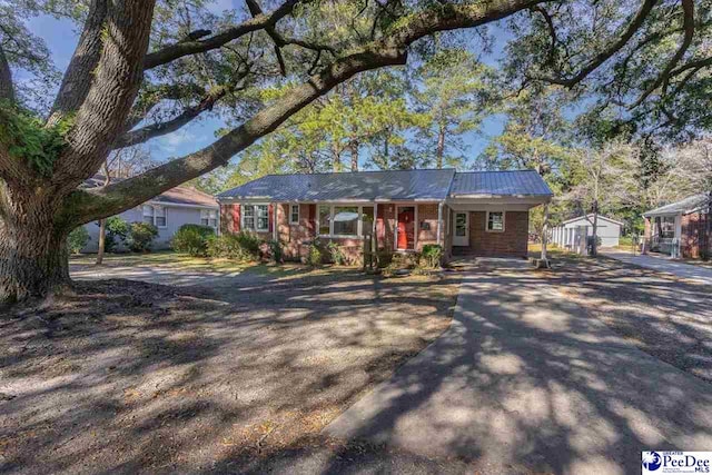 single story home featuring a porch, a garage, and an outbuilding