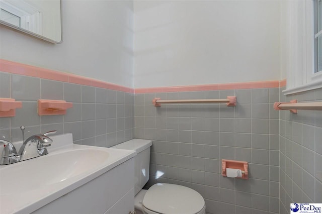 bathroom with vanity, tile walls, and toilet