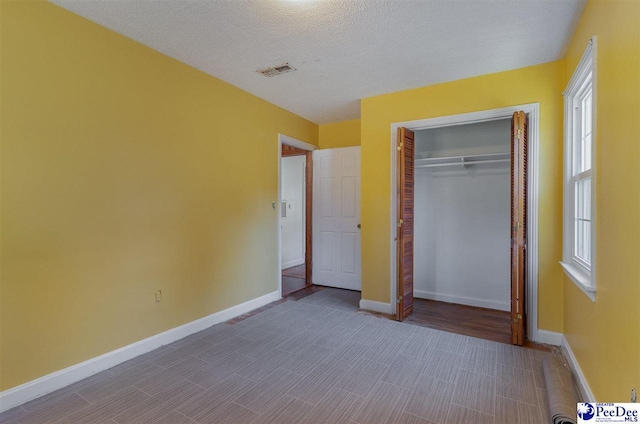 unfurnished bedroom with hardwood / wood-style floors, a closet, and a textured ceiling