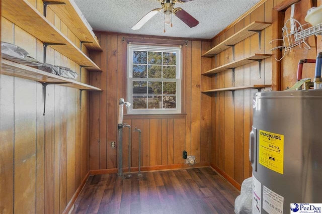 interior space with dark hardwood / wood-style flooring, electric water heater, a textured ceiling, and wood walls