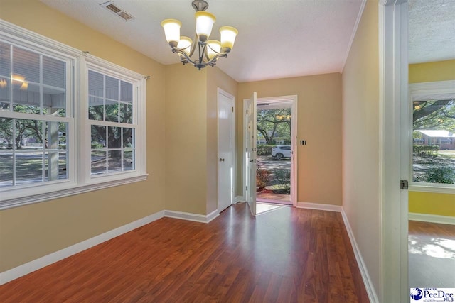 interior space with a notable chandelier, dark wood-type flooring, and a textured ceiling