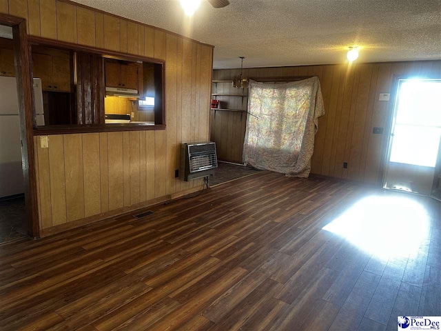 unfurnished living room featuring a textured ceiling, dark wood-style flooring, visible vents, and heating unit