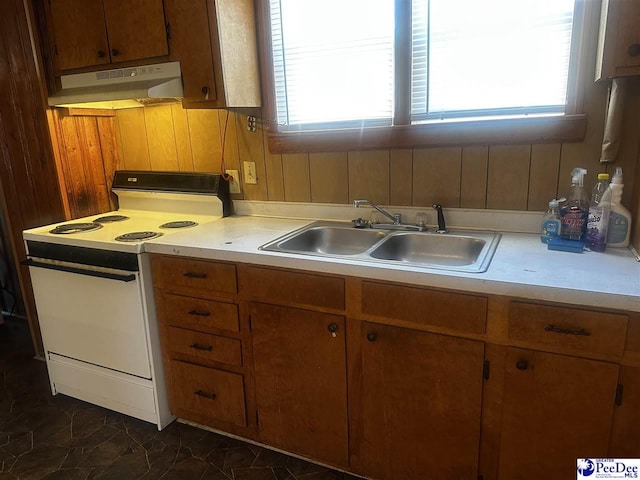 kitchen with under cabinet range hood, a sink, light countertops, a wealth of natural light, and white range with electric stovetop