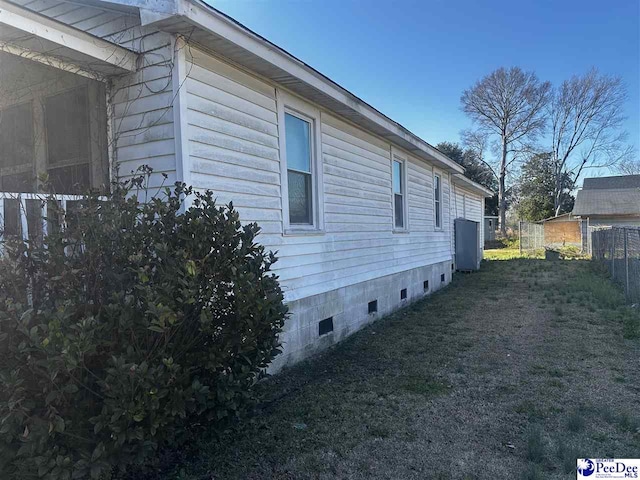 view of side of home with crawl space and fence