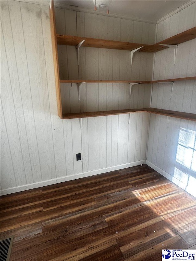 spare room with dark wood-style flooring, visible vents, and baseboards