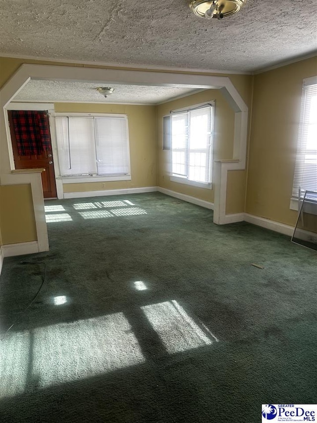 unfurnished room featuring baseboards, dark colored carpet, and a textured ceiling