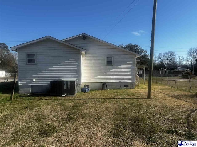 view of home's exterior featuring fence, central AC unit, and a lawn