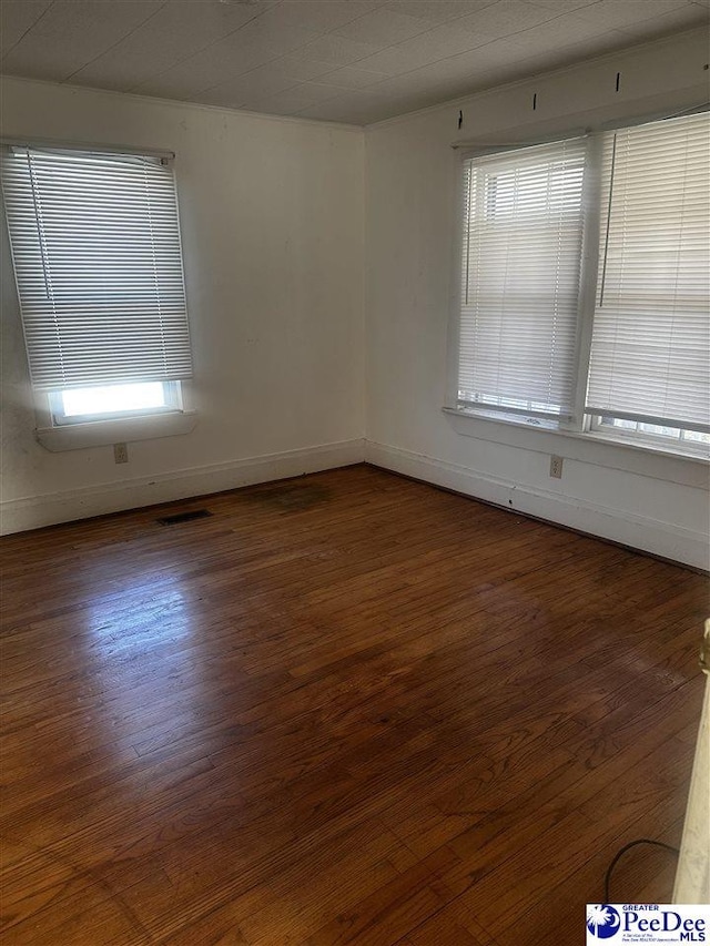 spare room with visible vents, dark wood finished floors, and baseboards