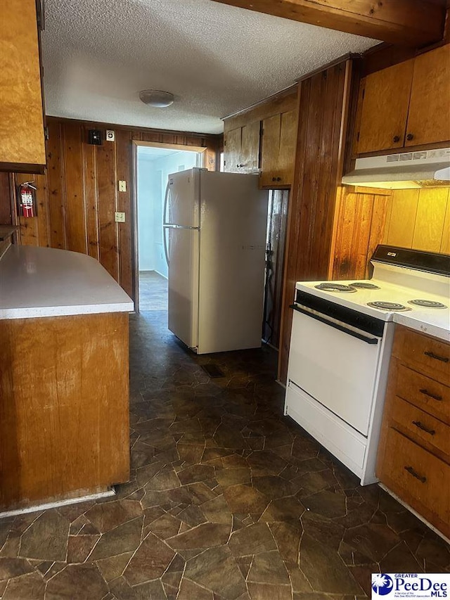 kitchen with brown cabinets, light countertops, wooden walls, white appliances, and under cabinet range hood