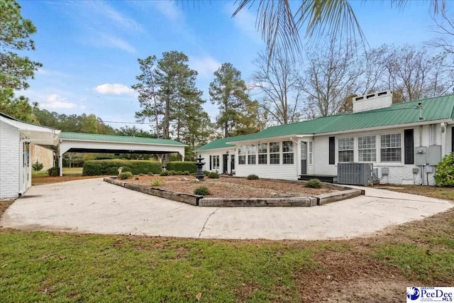 rear view of house with cooling unit and a lawn