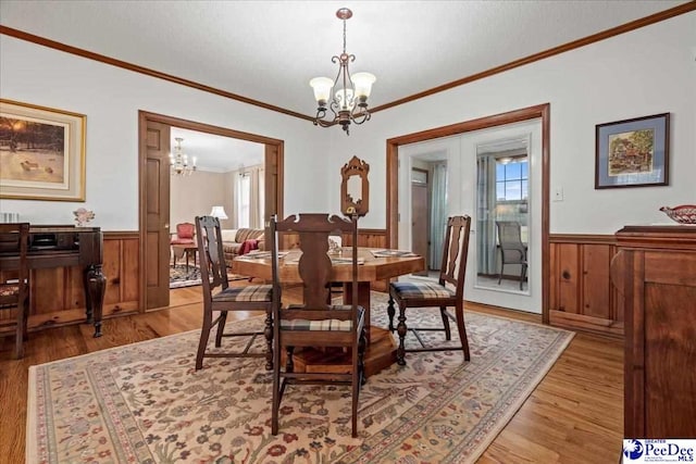 dining room with an inviting chandelier, crown molding, light hardwood / wood-style flooring, and french doors