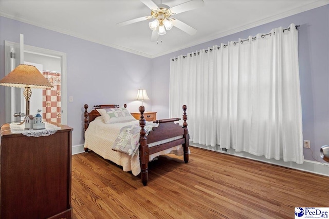 bedroom with hardwood / wood-style floors, ornamental molding, and ceiling fan