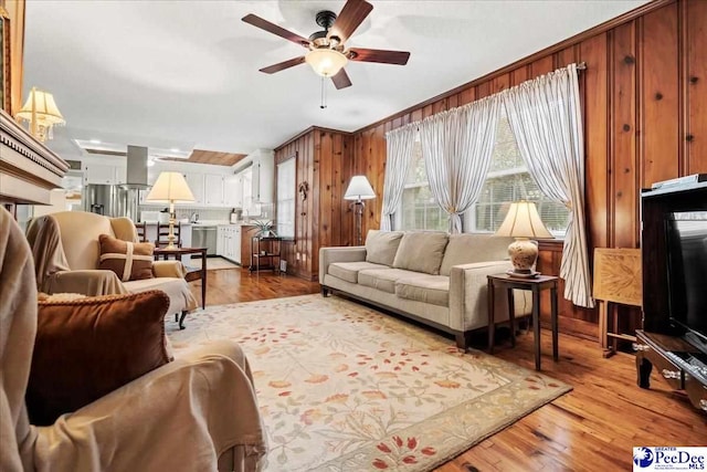 living room featuring hardwood / wood-style flooring, ceiling fan, and wood walls