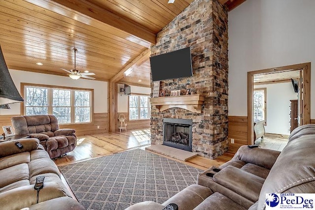 living room with a stone fireplace, wooden walls, wooden ceiling, and light wood-type flooring