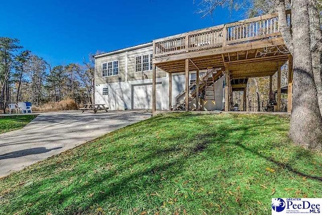 back of house featuring a wooden deck, a garage, and a lawn