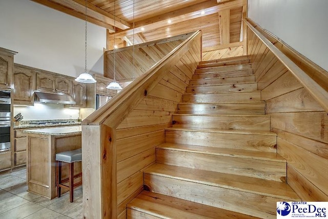 staircase featuring tile patterned floors and beam ceiling