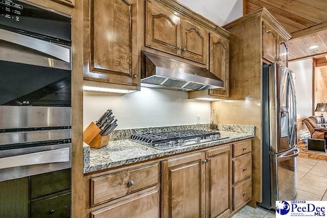 kitchen with stainless steel appliances, light tile patterned floors, and light stone counters