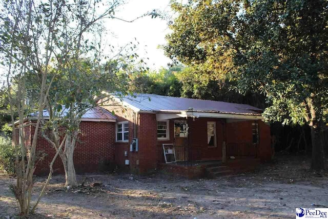 exterior space with metal roof, a porch, and brick siding