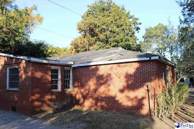 view of home's exterior with crawl space and brick siding