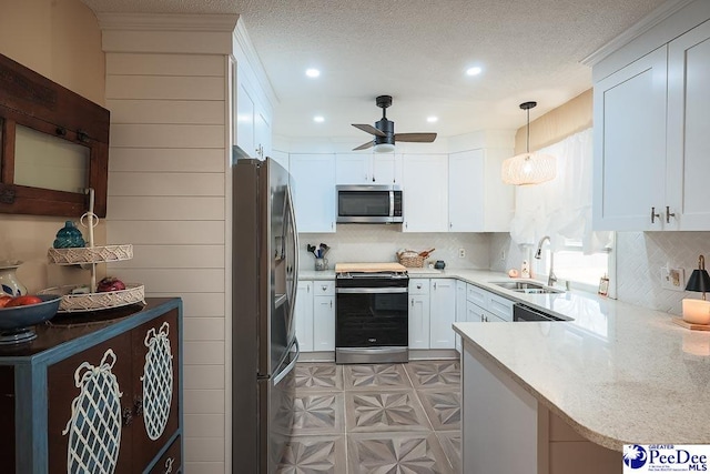 kitchen featuring light floors, appliances with stainless steel finishes, white cabinetry, a sink, and a textured ceiling