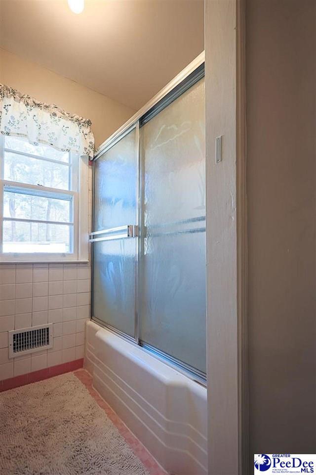 bathroom with combined bath / shower with glass door and visible vents