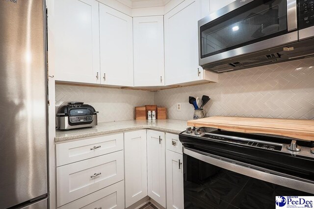 kitchen with tasteful backsplash, white cabinetry, and stainless steel appliances