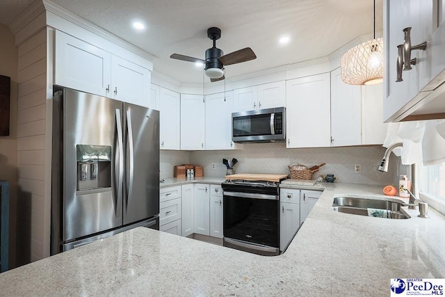 kitchen featuring white cabinets, appliances with stainless steel finishes, light stone counters, and a sink