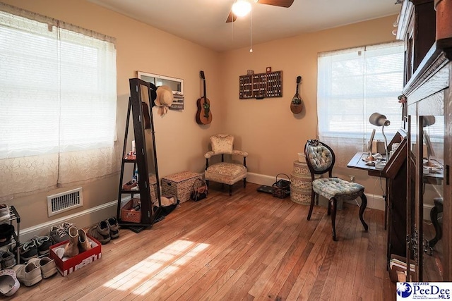 home office with ceiling fan, hardwood / wood-style flooring, visible vents, and baseboards